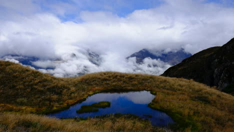 Lapso-De-Tiempo-De-Nubes-En-Las-Montañas-De-Nueva-Zelanda-Con-Tarn-Reflectante