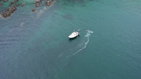 Wide-aerial-view-orbiting-a-jet-ski-and-small-boat-off-the-Cornish-coast-of-the-UK
