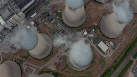 Pan-up-revealing-drone-shot-of-Large-power-plant-cooling-towers