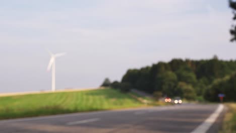Blurry-view-of-cars-driving-road,-windmill-in-background,-copy-space-for-titles