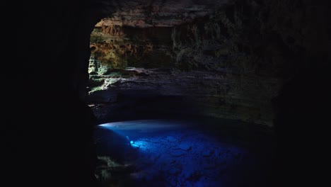 Tilting-up-shot-of-the-incredible-stunning-natural-cave-pool-the-Enchanted-Well-or-Poço-Encantado-in-the-Chapada-Diamantina-National-Park-in-Northeastern-Brazil-with-beautiful-clear-blue-water