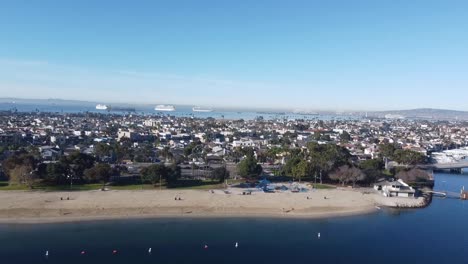 Drone-shot-over-beach-and-residential-neighborhood-with-ships-in-the-ocean