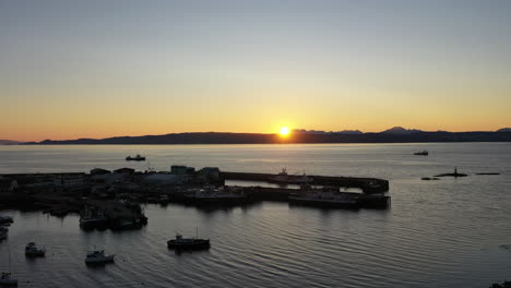 An-impressive,-sunset-drone-shot-of-Mallaig,-Scotland,-showing-the-town-and-Isle-of-Skye-in-the-distance