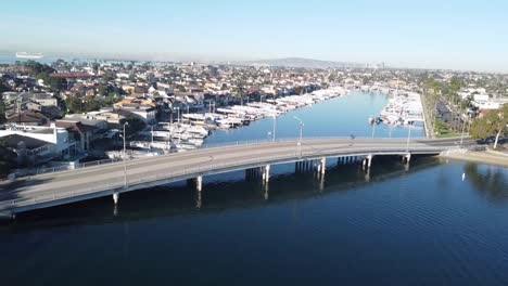 Fly-over-bridge,-houses-with-boat-docks,-drone-shot