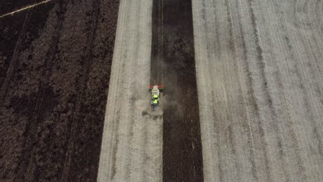 Birds-eye-view-of-a-combine-harvester-being-followed-by-exhaust-fumes-as-it-harvests-feed-beans