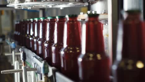 Row-of-bottled-juice-refreshment-on-production-line-and-automatic-machine-working-in-beverage-processing-factory