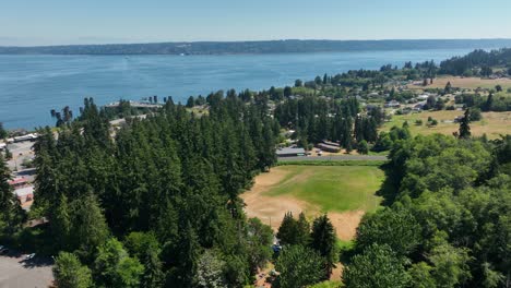 Aerial-shot-above-a-forest-with-a-baseball-field-clearing-underneath-on-Whidbey-Island