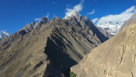 Cinematic-drone-shot-of-Tupopdan-Peak,-Passu-Cones-in-Hunza-Pakistan,-snow-covered-mountain-peaks-with-steep-cliffs,-high-wide-aerial-shot-with-shadows-on-the-ridges