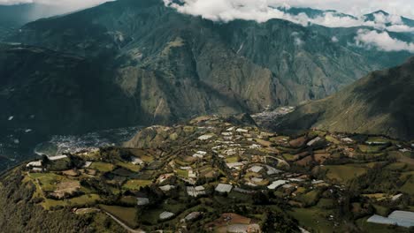 Aerial-View-Of-Town-With-Lush-Green-Fields-And-Tungurahua-Volcano-In-Background-In-Ecuador---drone-shot