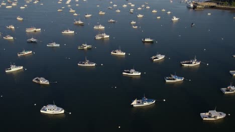 Aerial-view-over-anchored-boats-on-the-coast-of-Plymouth,-sunset-in-Massachusetts,-USA---tilt,-drone-shot