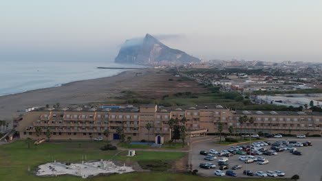 Sunset-drone-shot-rising-up-and-zoomed-in-above-beach-resort-looking-south-towards-Africa-from-Spain-with-the-rock-of-Gibraltar-in-view