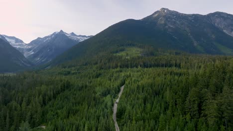 Road-Through-Greenery-Forest-In-Highway-99-With-Towering-Mountainscape-Background-In-British-Columbia,-Canada