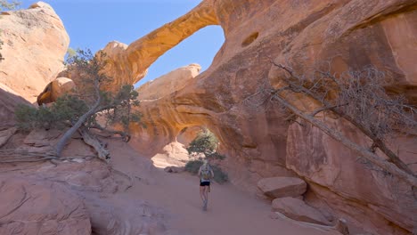 Joven-Excursionista-Rubia-En-Los-Arcos-Dobles-En-El-Parque-Nacional-Arches,-Utah