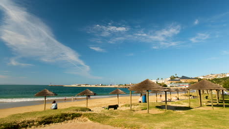 Thatched-umbrellas-on-popular-tourist-beach,-Santos,-Mossel-Bay