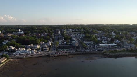 Aerial-view-over-sea,-towards-the-coast-of-the-Plymouth-town,-summer-evening-in-MA,-USA