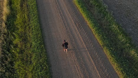 Male-drone-pilot-walking-along-a-dirt-road-in-rural-Alberta-at-sunset