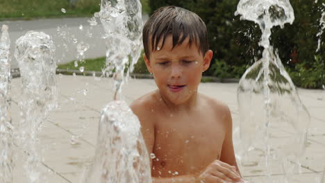Ein-Kleiner-Junge,-Der-Vom-Wasserfluss-Des-Stadtbrunnens-Fasziniert-Ist