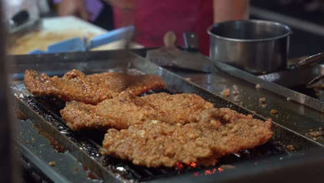 Honey-soy-coated-delicious-fried-chicken-fillet-grilling-on-hot-grill,-professional-chef-brush-tasty-sauce-on-the-meat-and-flip-side-with-a-pair-of-tongs-at-famous-night-market,-Taiwan,-Asia
