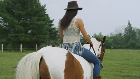 Confident-female-horse-rider-riding-a-horse-bareback-through-a-field