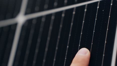 Person-finger-touching-solar-panel-cell-in-close-up-macro-view
