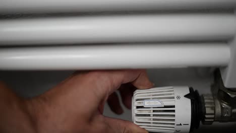 Hand-turning-dial-turning-off-home-radiator-to-lower-temperature-and-oil-consumption