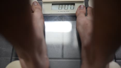 Close-up-of-feet-stepping-onto-a-digital-bathroom-scale-on-grey-tiles