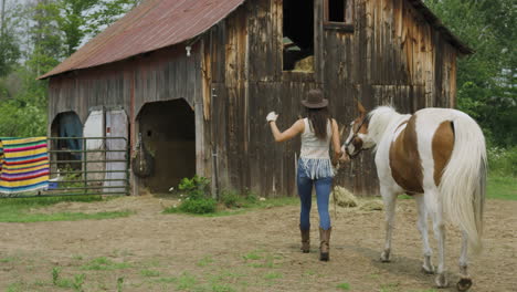 Confident-and-stylish-young-rider-walks-her-pinto-horse-back-to-the-horse-barn