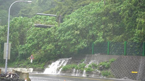 Typhoon-approaching,-bad-visibility-and-dangerous-driving-condition-with-heavy-rainfall-that-developed-a-little-falls-on-the-roadside-at-Hsuehshan-Tunnel-at-Hualien-City,-Taiwan