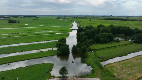 Pullback-aerial-view-of-a-boat-on-a-canal-between-slagenlandschaps-in-a-large-polder-in-the-Krimpenerwaard-region-of-the-Netherlands