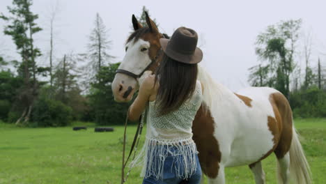 Trained-woman-rider-bonding-with-her-male-pinto-horse,-ruffling-his-mane