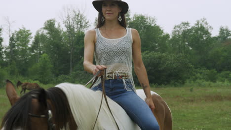 Stylish-confident-cowgirl-rides-her-horse-bareback,-walking-slowly-past-the-camera