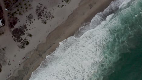 Aerial-is-rotating-in-birdview-over-Playa-Zicatela-showing-the-huge-waves,-puerto-Escondido,-Mexico