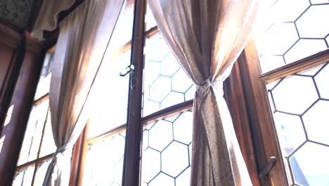 A-tilt-up-shot-of-an-antique-window-and-curtains