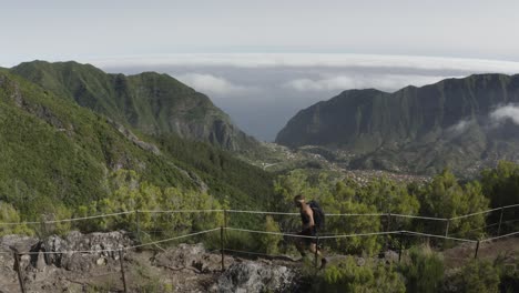 Drone-shot-of-the-landscape-at-Caminho-Do-Pinaculo-e-Foldhadal-in-Madeira-with-a-fit-and-strong-man-walking-on-the-rocky-path-on-the-top