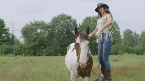 Cowgirl-mounting-her-adult-pinto-horse-in-a-field-1