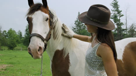 Trained-young-cowgirl-lightly-grooms-her-pinto-horse's-mane