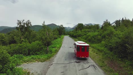 Tranvía-Rojo-Conduciendo-Por-Una-Carretera-Rodeada-De-Exuberante-Vegetación-En-Alaska---Seguimiento