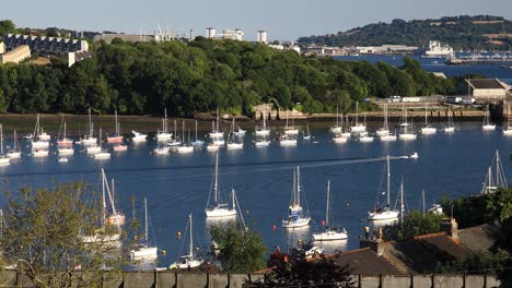 A-Small-Boat-Travels-Down-the-River-Tamar-Between-Devon-and-Cornwall-with-Many-Yachts-on-Either-Side-Between-Devon-and-Cornwall