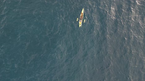 Aerial-drone-top-down-view-of-a-yellow-fishing-kayak-in-the-Pacific-Ocean