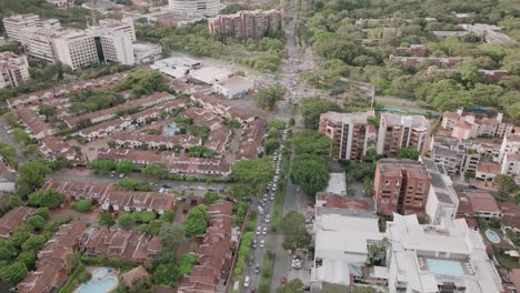 Slow-aerial-pan-up-of-traffic,-apartment-buildings-and-the-mall-in-the-suburbs-on-Cali,-Colombia