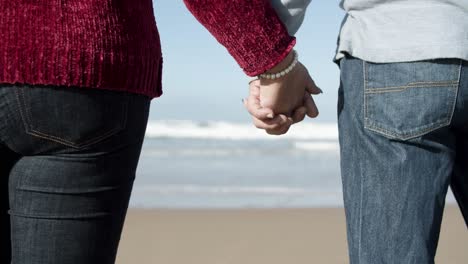 Latin-couple-holding-hands-while-standing-in-the-beach-with-the-in-the-background,-loving-moments-concept