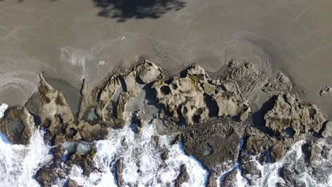 Verkleinern-Luftaufnahme-Von-Strandwellen,-Die-Gegen-Felsen-Schlagen
