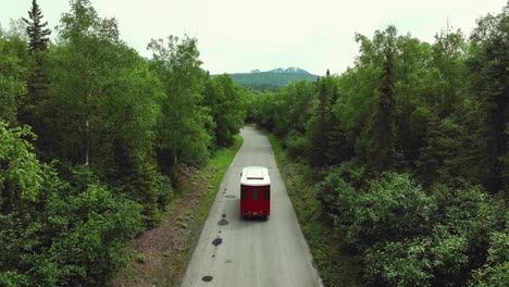 Malerische-Landschaft-Mit-Rotem-Oberleitungsbus,-Der-Auf-Der-Straße-In-Alaska-Fährt---Kamerafahrt