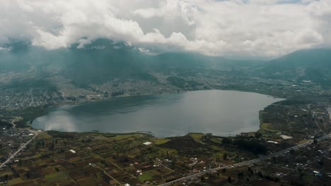 Laguna-De-San-Pablo-Mit-Vulkan-Imbabura-Gegen-Bewölkten-Himmel-In-Otavalo,-Ecuador---Drohnenaufnahme