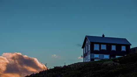 Chalet-Oder-Hütte-Am-Berghang-In-Der-Abenddämmerung-Mit-Vorbeiziehenden-Wolken---Zeitraffer