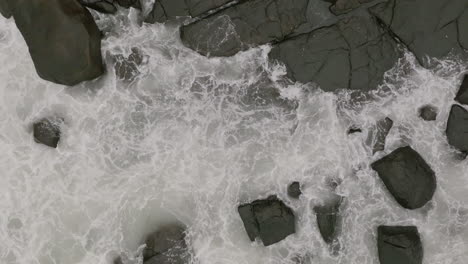 Nahaufnahme-Von-Luftaufnahmen-In-Zeitlupe-Von-Oben-Nach-Unten-Von-Meereswellen,-Die-Gegen-Felsen-Prallen
