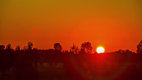 A-bright,-fiery-sunset-over-the-countryside-turns-to-orange-at-dusk---time-lapse