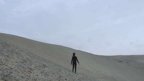 Long-shot-of-a-woman-dressed-in-black-in-the-desert-in-the-middle-of-nowhere-with-the-wind-blowing-hard