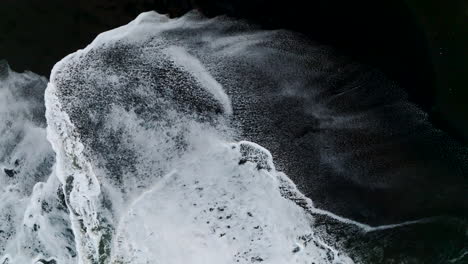 Seitlicher-Winkel,-Vogelperspektive-Luftaufnahme-Von-Shite-Tide,-Die-Auf-Einen-Kontrastierenden-Schwarzen-Sandstrand-In-Bali-Stürzt