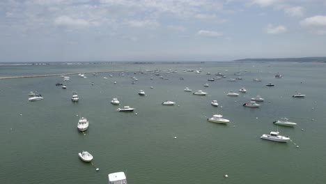 Anchored-boats-at-the-port-of-Plymouth,-sunny-Massachusetts,-USA---reverse,-aerial
